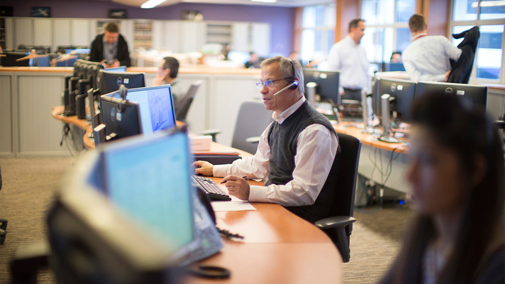Man sitting at a desk in a call center talking on a headphone