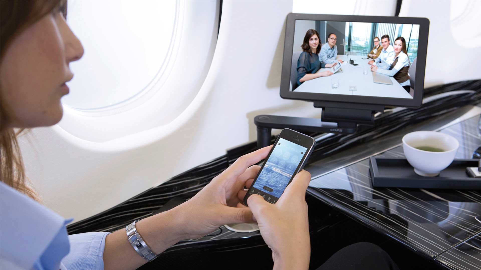 Woman using her phone while on a video conference call while onboard a Falcon