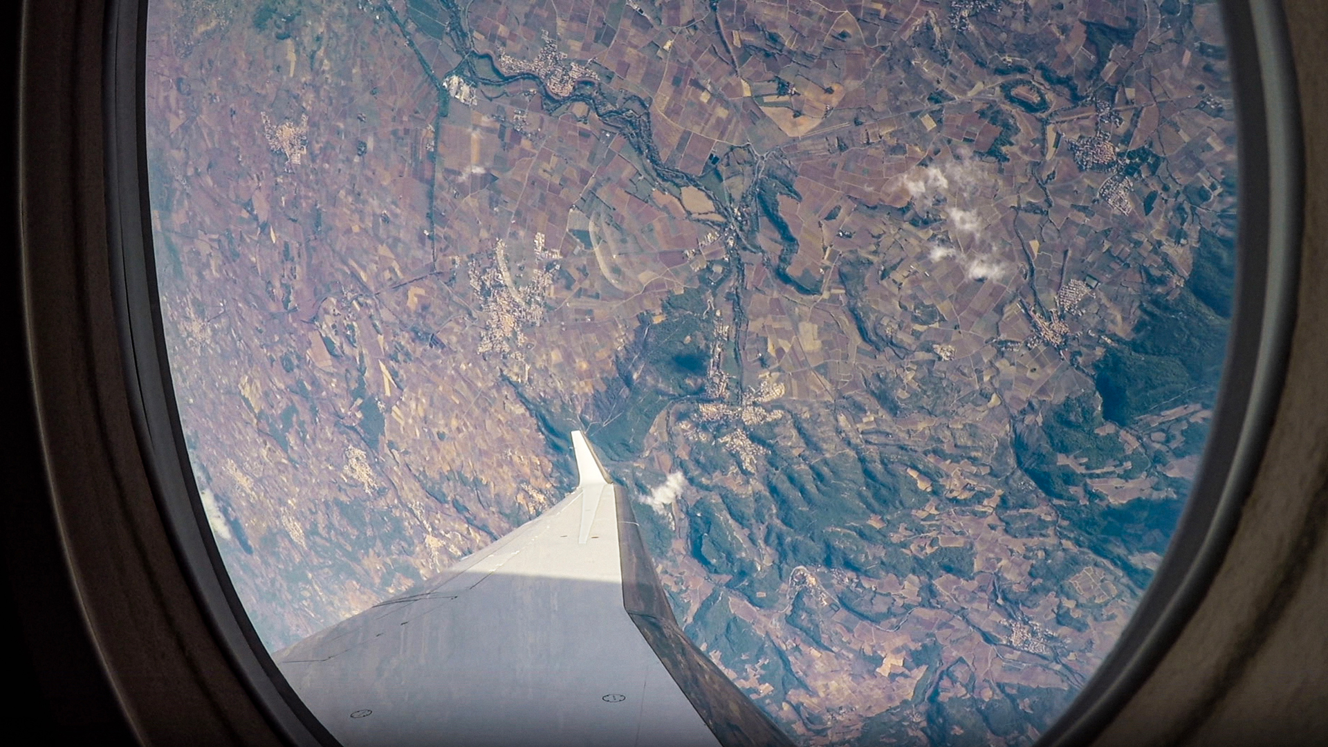 Image shows the view of the ground from looking through an aircraft window as the aircraft makes a very sharp right turn