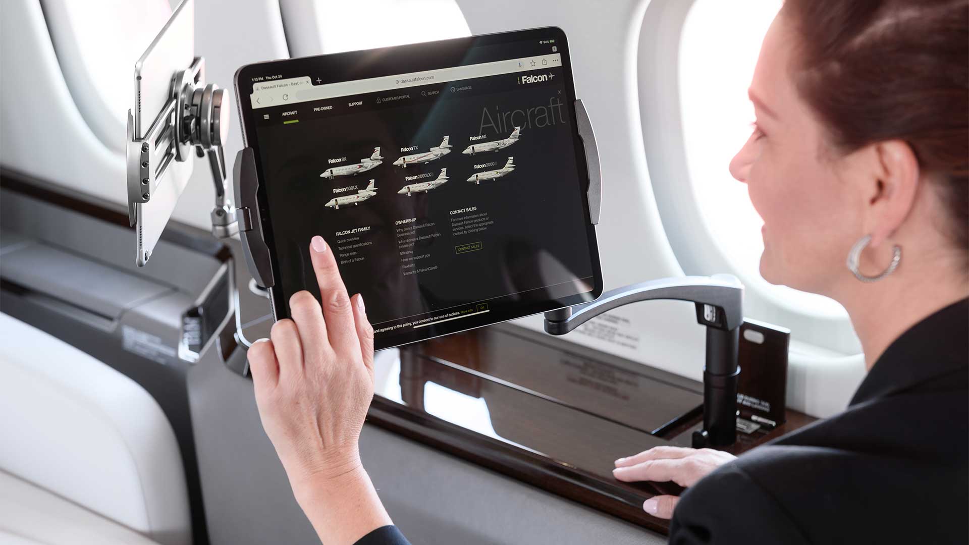 A woman sits on a Falcon luxury business jet using her iPad attached to an Ingenio iPad arm.