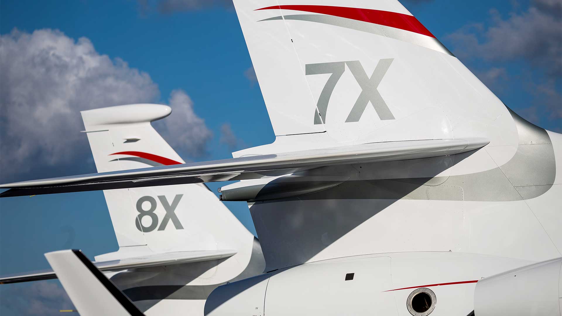 View of the tail section of a Falcon 8X parked beside a Falcon 7X.